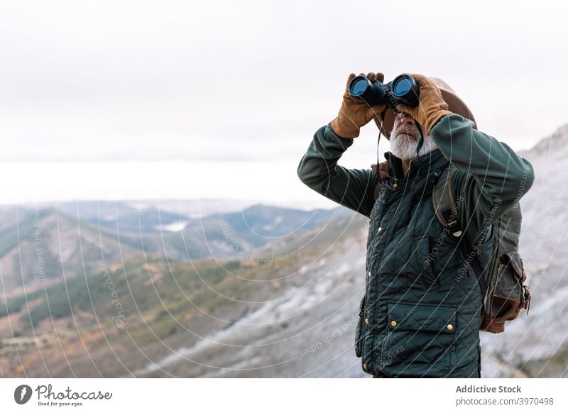Älterer Mann schaut durch ein Fernglas in den Bergen Berge u. Gebirge Reisender beobachten bewundern Hochland Winter Senior Oberbekleidung männlich Cacere