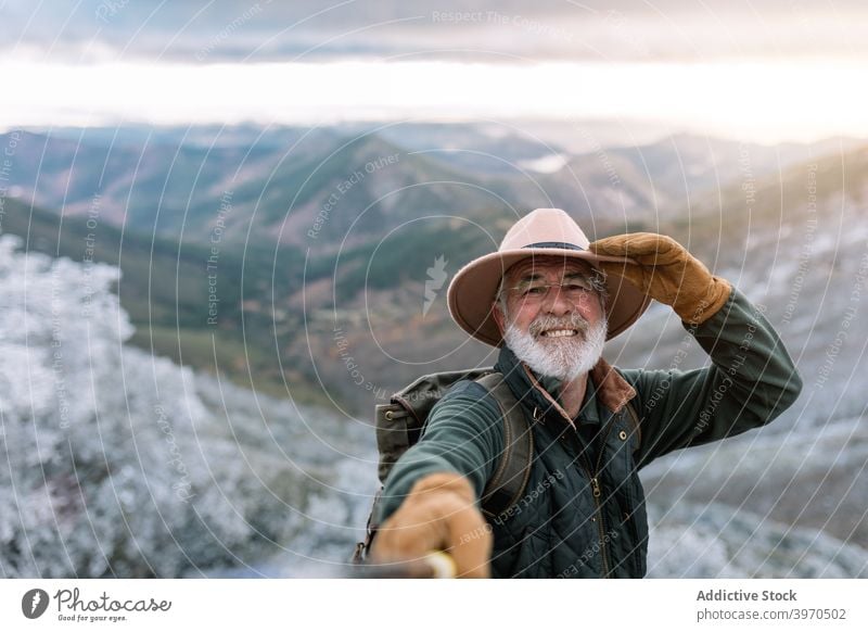 Fröhliche ältere Reisende nehmen Selfie in den Bergen Senior Reisender Berge u. Gebirge Mann heiter Selfie-Stick Selbstportrait Winter Hochland männlich Cacere