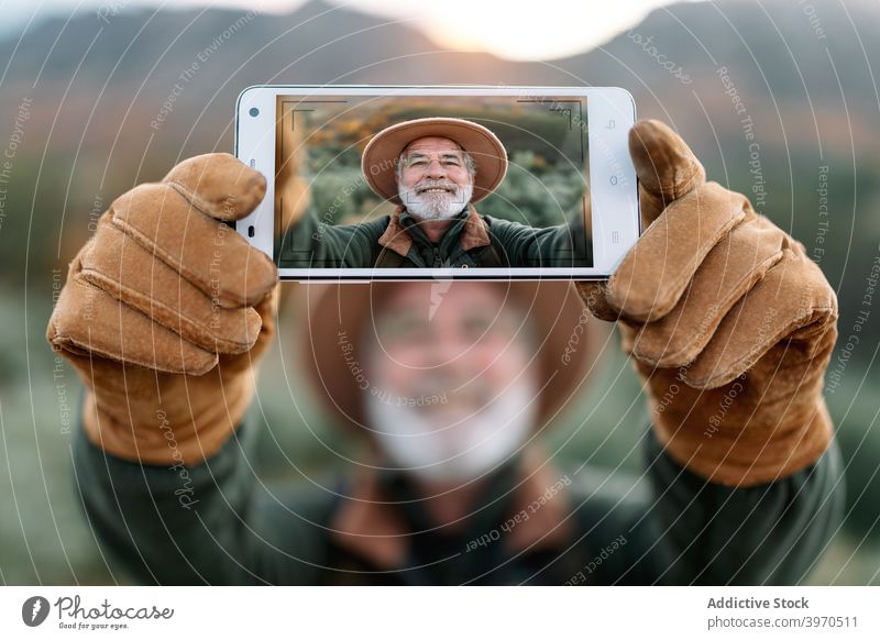 Älterer Mann nimmt Selbstporträt auf Smartphone in der Natur Reisender Fotografie Selfie heiter Senior Berge u. Gebirge Anzeige Urlaub männlich Cacere