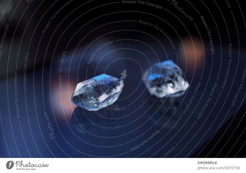zwei Kristalle, die auf einer dunklen Spiegelfläche liegen Edelstein Mineral Detailaufnahme Schmuck schließen Juwel Geologie dunkel natürlich Hexerei geistig
