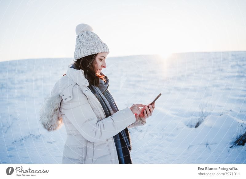 schöne junge Frau bei Sonnenuntergang in verschneiten Berg mit Handy. Natur und Technik Konzept. Wintersaison Technik & Technologie Berge u. Gebirge Schnee