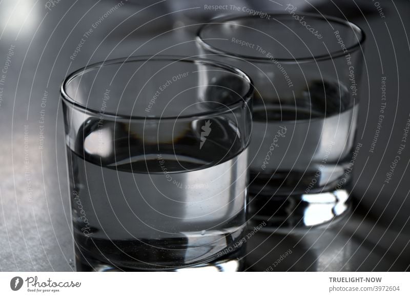 Zwei nüchterne Gläser mit klarem Trinkwasser gefüllt spiegeln und reflektieren fast farblos etwas Tageslicht Wasser Glas Wasserglas kühl trinken Lebensmittel