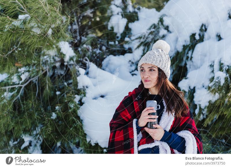 schöne Frau in karierte Decke gewickelt hält Thermoskanne mit heißem Getränk. Natur und Lifestyle heißer Tee Berge u. Gebirge trinken sonnig Schnee wandern