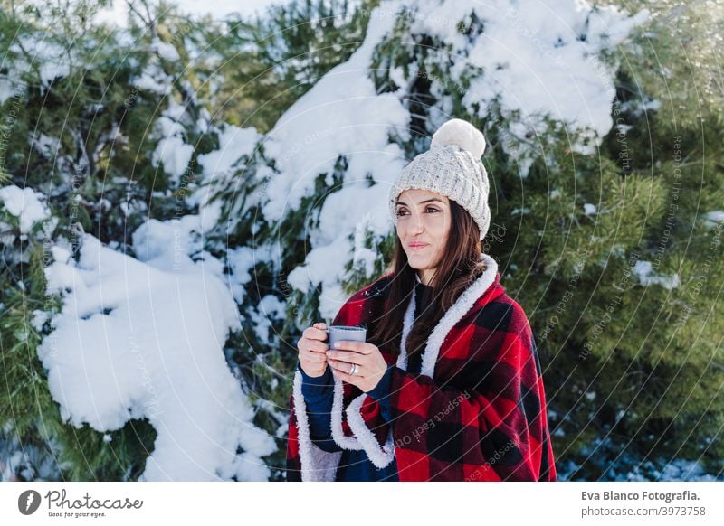 schöne Frau in karierte Decke gewickelt hält eine Tasse heißen Kaffee. Natur und Lifestyle Schnee Berge u. Gebirge Plaid heißer Tee Thermoskanne trinken sonnig