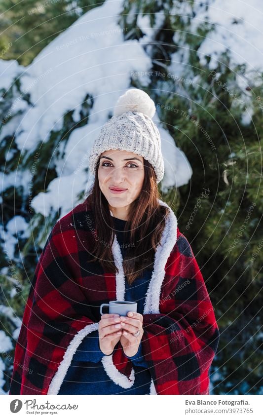 schöne Frau in karierte Decke gewickelt hält eine Tasse heißen Kaffee. Natur und Lifestyle Schnee Berge u. Gebirge Plaid heißer Tee Thermoskanne trinken sonnig