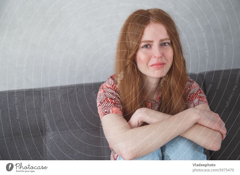 Junge traurige depressive kaukasische Frau Porträt mit Tränen in den Augen sitzen auf Sofa umklammert Ihre Knie Mädchen junger Schrei deprimiert schön