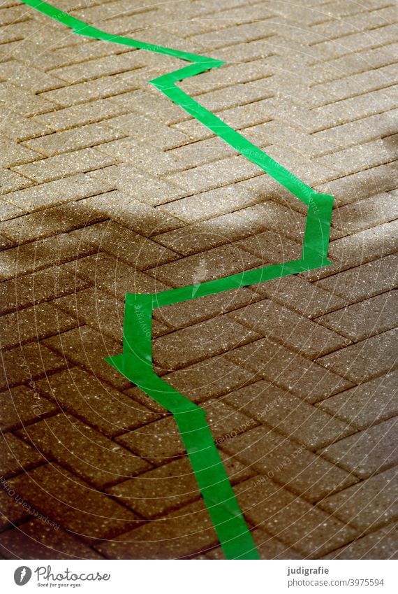 Zickzack in grün auf Straßenpflaster Linie Markierung Markierungslinie Wege & Pfade Pflastersteine gepflastert Schatten Licht Stadt Stein Grenze Muster