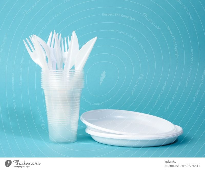 Einweggeschirr aus weißem Kunststoff Teller, Tassen, Gabeln und Messer auf einem blauen Hintergrund Dienst Kulisse Stapel Geschirr Werkzeug Utensil Ware kreisen