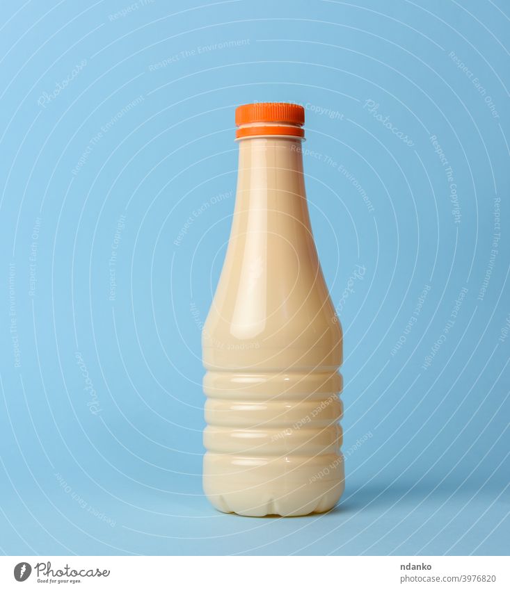 beige Plastikflasche für Milch auf blauem Hintergrund, melken Flasche Kunststoff Getränk Flüssigkeit modern übersichtlich Verpackung zugeklappt liquide trinken