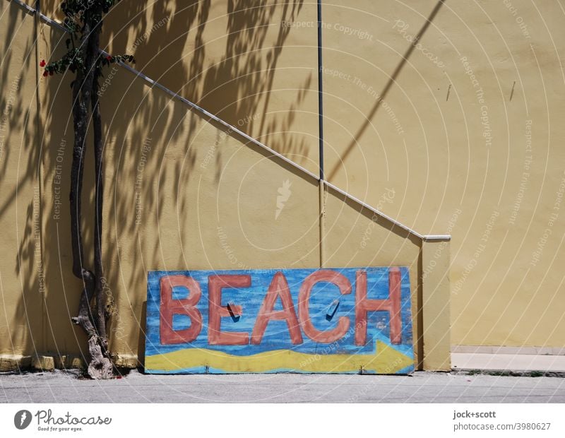 Bemaltes Holzschild mit Wegweiser zum Strand Hinweis Holzbrett Wort selbstgemacht Pfeil gemalt Baumstamm Schattenspiel Treppenaufgang Architektur Wand