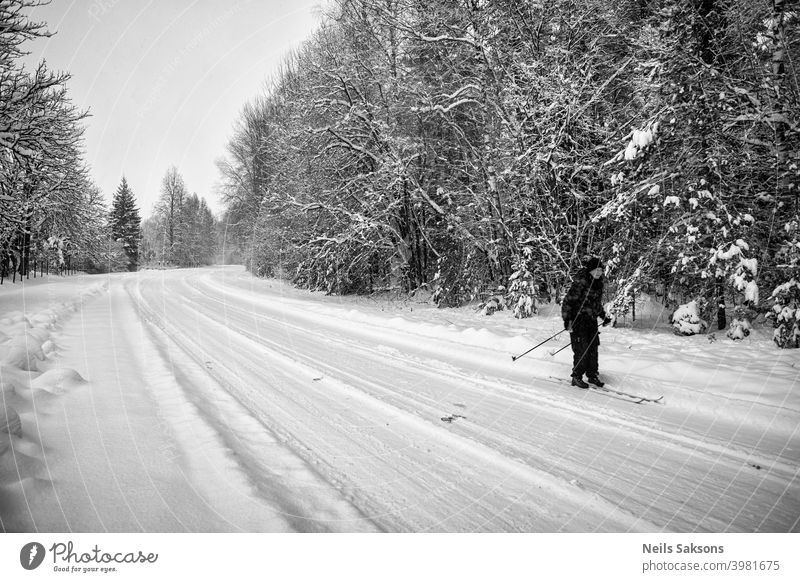 Frau beim Skifahren auf leerer Landstraße Aktion aktiv Aktivität Erwachsener Lettland blau hell Kabel Stuhl kalt Konkurrenz durchkreuzen Tag bergab Europa
