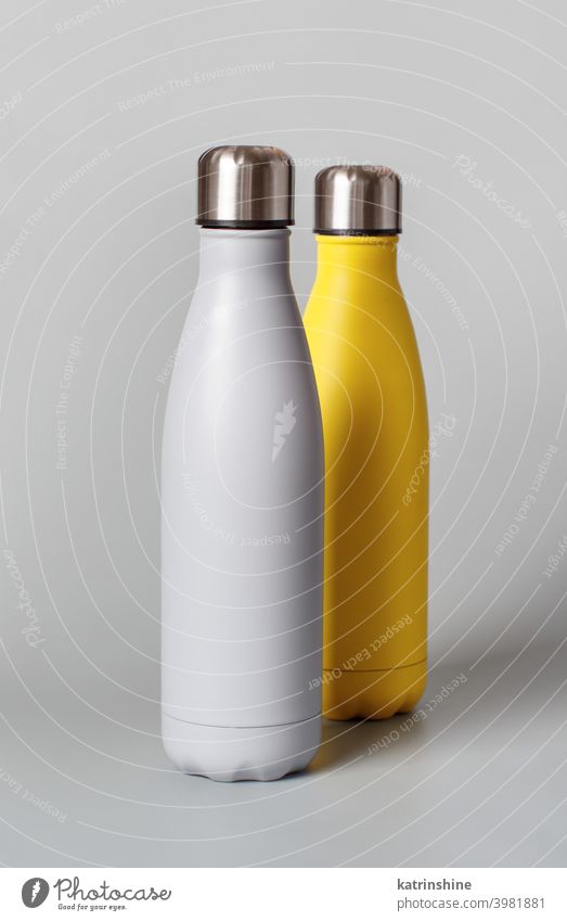 Graue und gelbe wiederverwendbare Flaschen auf grauem Hintergrund Monochrom Attrappe isoliert ökologisch Wasser Stahl Thermo Leichtmetall blanko abschließen