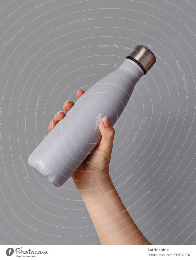 Hand mit grauer, gespülter Flasche auf grauem Hintergrund wiederverwendbar Monochrom Attrappe gelb isoliert ökologisch Wasser Stahl Thermo Leichtmetall blanko