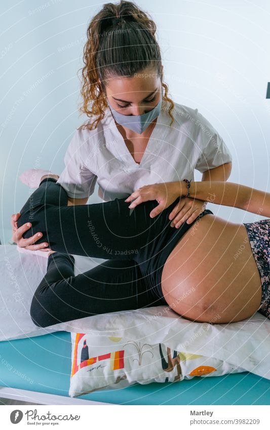 Weibliche Therapeutin dehnt das Bein einer Schwangeren während einer Physiotherapie-Sitzung in einer modernen Klinik. Schwangerschaft schwanger pränatal