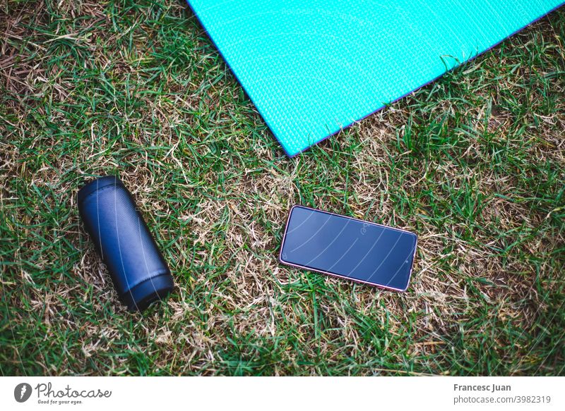 Hohe Winkelaufnahme einer Yogamatte, eines Smartphones und eines Lautsprechers hoch vertikal schwarz rot Holz hölzern Tisch Musik Mobile Telefon Anzeige