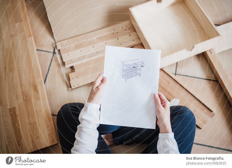 Junge Frau beim Zusammenbau von Möbeln zu Hause lesen Anweisungen. DIY-Konzept Tisch Hammer es selbst machen diy heimwärts Kaukasier im Innenbereich arbeiten