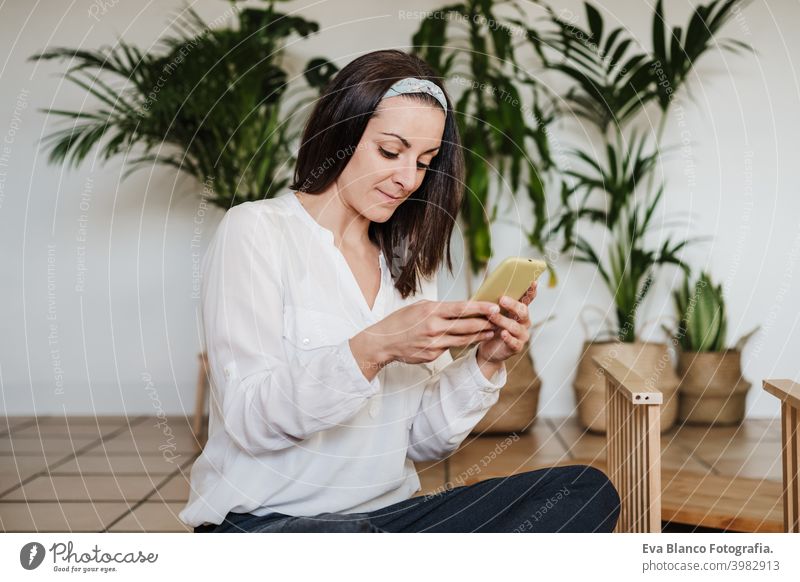 junge Frau beim Zusammenbau von Möbeln zu Hause lesen Anweisungen auf dem Handy. DIY-Konzept es selbst machen heimwärts Technik & Technologie Internet