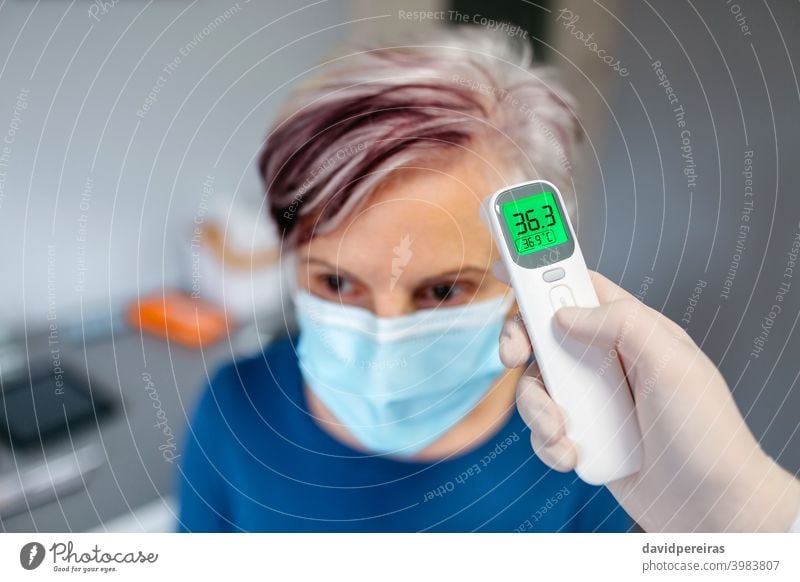 Ältere Frau ohne Fieber, deren Temperatur mit einem Infrarotthermometer gemessen wird Senior kein Fieber berührungsloses Thermometer Arzt covid-19 Gesundheit