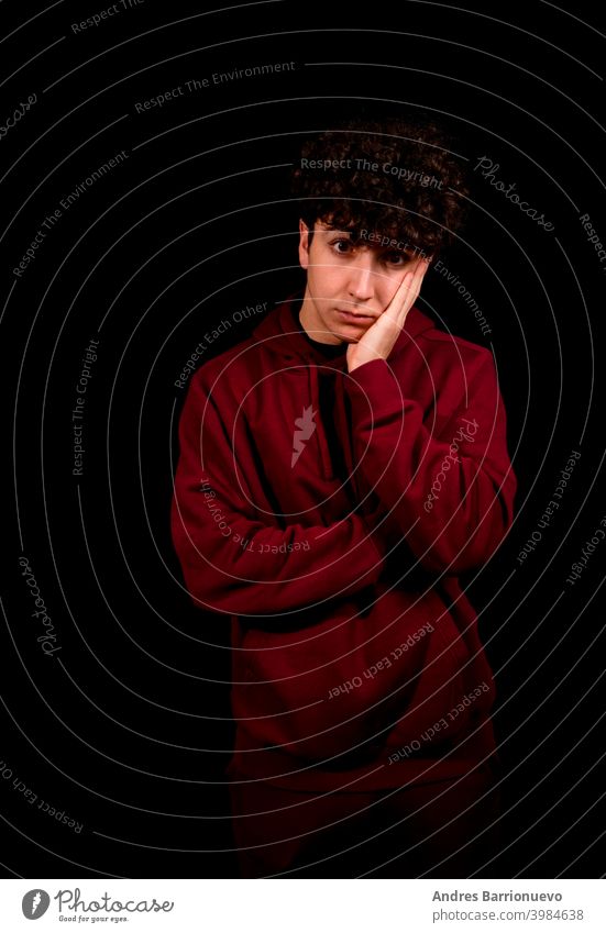 Attraktiver junger Mann mit lockigem Haar posiert auf schwarzem Studio Hintergrund Kaukasier Nahaufnahme nachdenklich Typ Blick Menschen kurz attraktiv