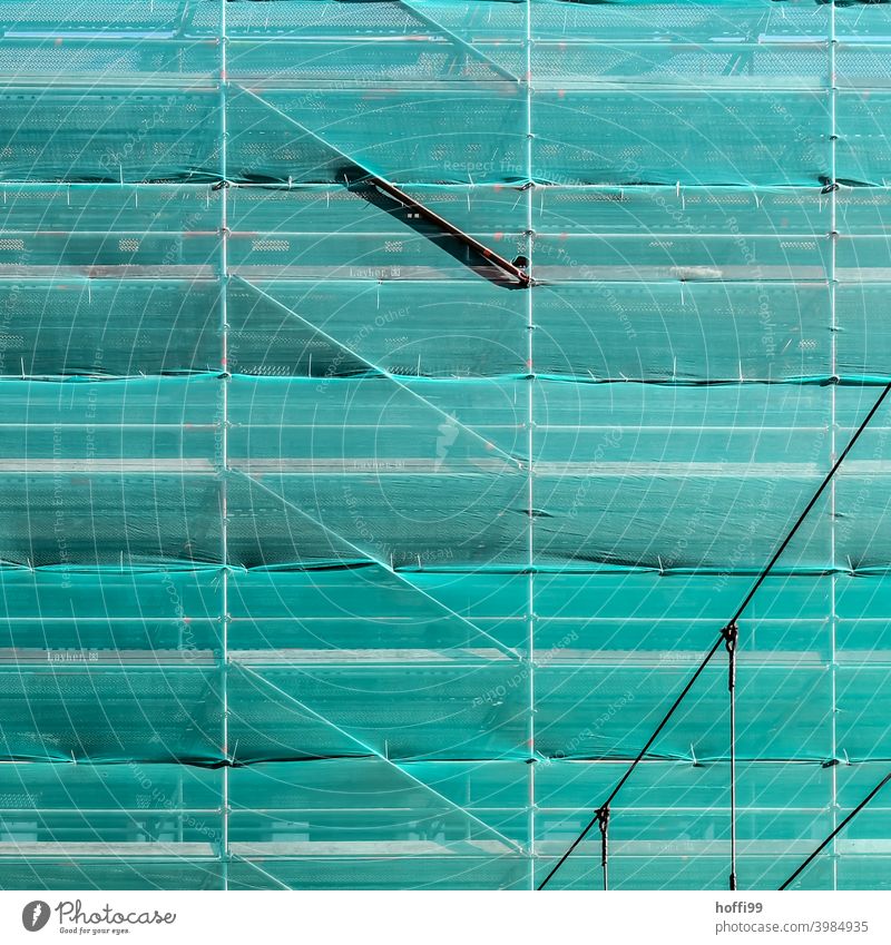 grünes Sicherheitsnetz vor einer eingerüsteten Fassade Netz Baustelle Gerüst Gerüstplane Baugerüst Strukturen & Formen Renovieren Abdeckung Gebäude Sanieren