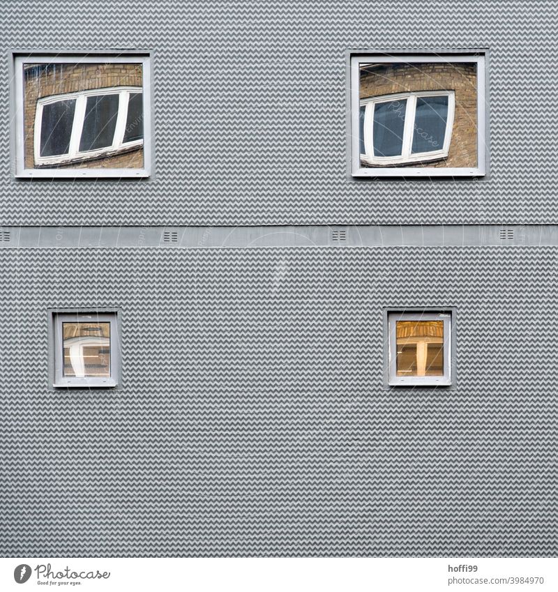 graue Fassade mit sich in den Fenstern spiegelnden Fenstern Architektur exotisch Armut geheimnisvoll Irritation Symmetrie Gedeckte Farben außergewöhnlich trist