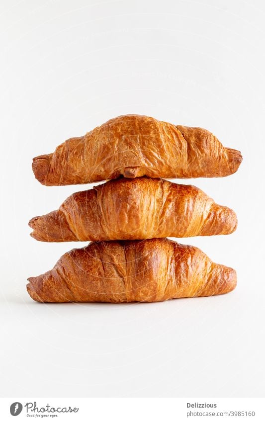 Drei frisch gebackene Croissants übereinander gestapelt auf einem weißen Hintergrund mit Kopierraum, Nahaufnahme Gebäckstück Bäckerei Brot Frühstück braun