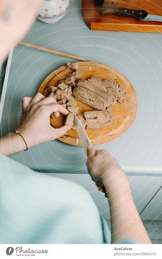 Eine Frau schneidet beim Kochen mit einem Messer etwas Tofu über eine runde Holzplatte Diner Schauplatz horizontal Respekt Fälschung speisend Sellerie Niemand