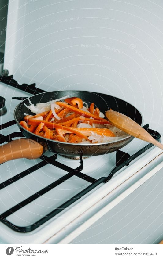 Eine Pfanne gefüllt mit leckerem Paprika und Zwiebeln beim Kochen in der Küche horizontal Arbeitsplatz Desktop Person im Innenbereich Spargel im Inneren Blick