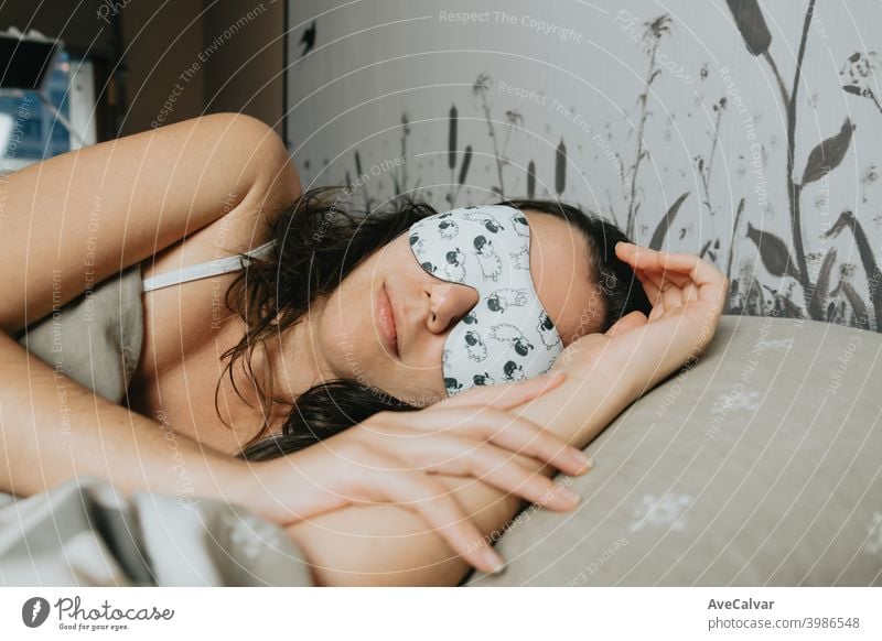 Eine junge Frau, die mit einer weißen Schlafmaske auf dem Bett schläft träumen Frieden Wellness Jugend schlafend gut Lächeln Augenbinde Ausdruck Gleichgewicht