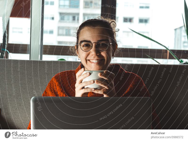 Eine junge Frau lächelnd vor seinem Laptop in der Couch, während er eine Tasse Kaffee hält Dokumente horizontal Job lebend entspannt forschen gelungen Lehrer