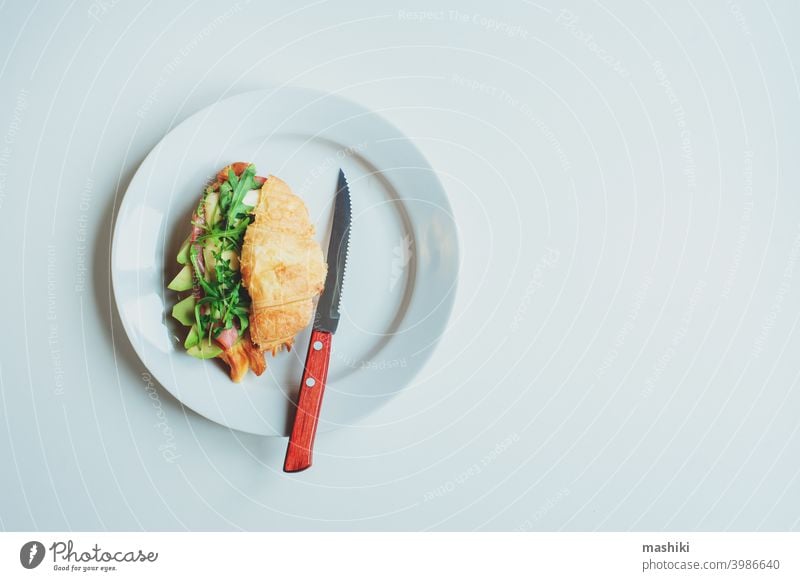 gesundes leckeres Frühstück - Croissant mit Avocado, Rucola, Schinken und Käse auf weißem Teller Belegtes Brot Lebensmittel Mahlzeit Snack Mittagessen Gemüse