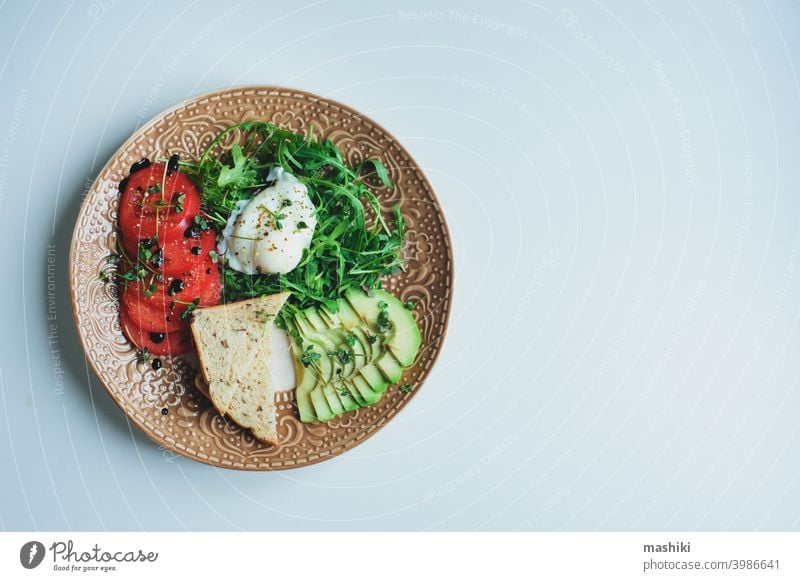 gesunde Ernährung vegetarisches Frühstück - pochiertes Ei, Vollkornbrot, Tomaten, Avocado, Rucolasalat mit Olivenöl und Mikrogrün Gemüse Lebensmittel