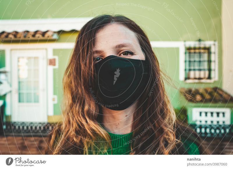 Bild einer Frau in Rot mit einer schwarzen Gesichtsmaske Pandemie COVID Coronavirus Mundschutz grün ansteckend Grippe Erkältung infektiös neue Normalität reisen