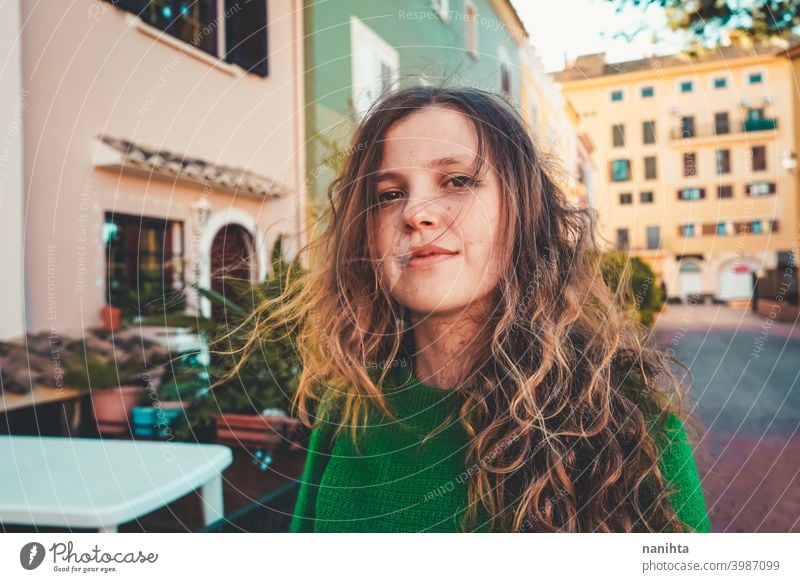 Junge Frau trägt grünen Oversize-Pullover und genießt einen windigen Tag in einer bunten Stadt reisen Porträt Lifestyle Model Europa Europäer blond im Freien