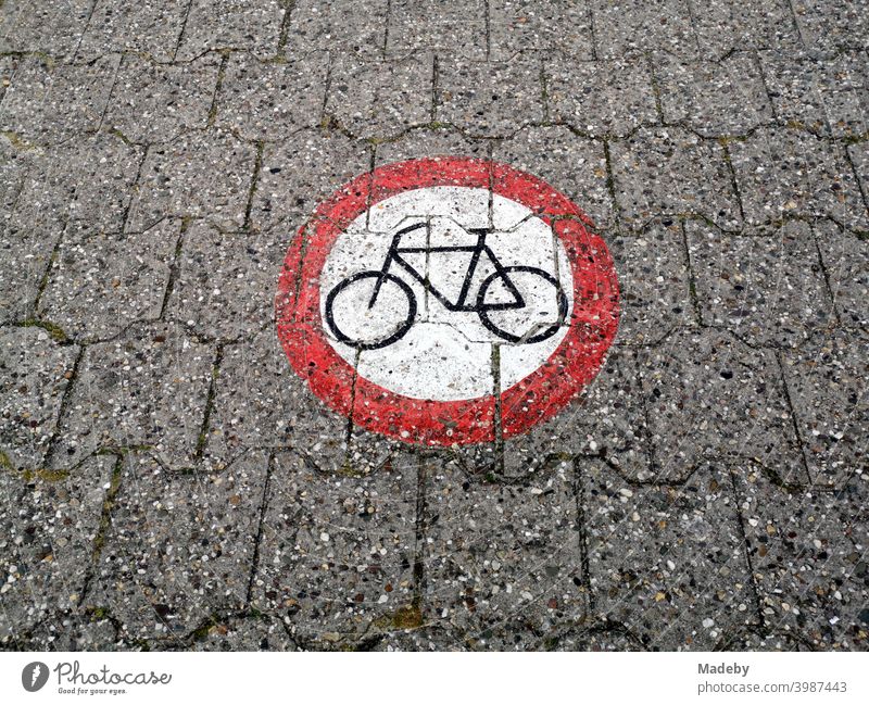 Ein rundes Verkehrszeichen auf das Verbundpflaster gemalt verbietet die Durchfahrt für Fahrräder auf dem Deich am Hafen von Neuharlingersiel bei Esens in Ostfriesland im Kreis Wittmund in Niedersachsen