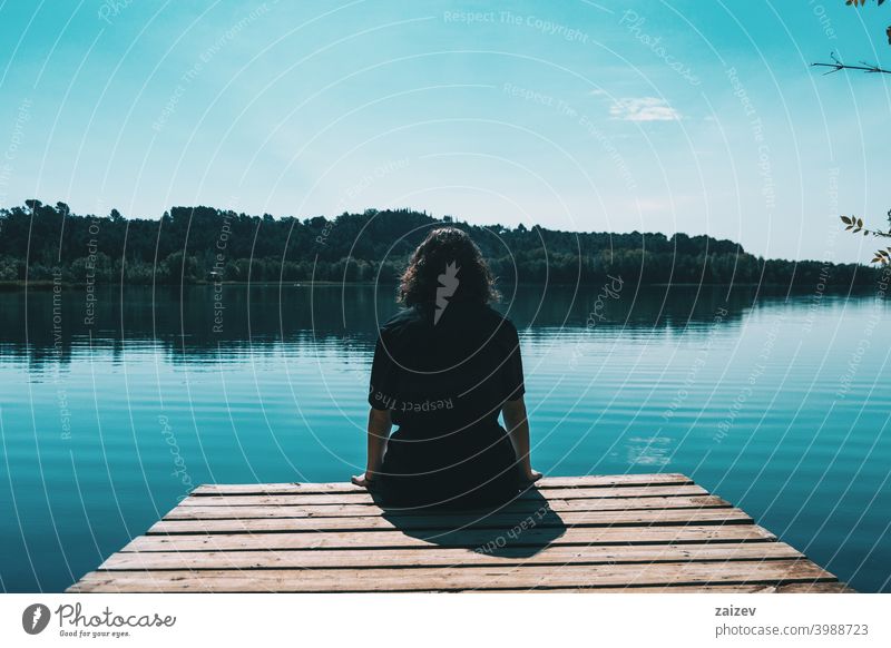 Mädchen sitzt auf dem Rand des Banyoles See mit der Landschaft im Wasser reflektiert Harmonie Meditation entspannend horizontal Profil Ruhe Person nachdenken