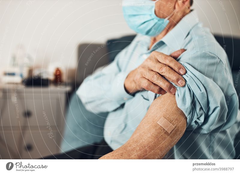 Älterer männlicher Patient, der den Hemdsärmel mit einem Pflaster anstelle einer Impfstoffinjektion hochhält. Impfung gegen Covid-19 oder Coronavirus geduldig