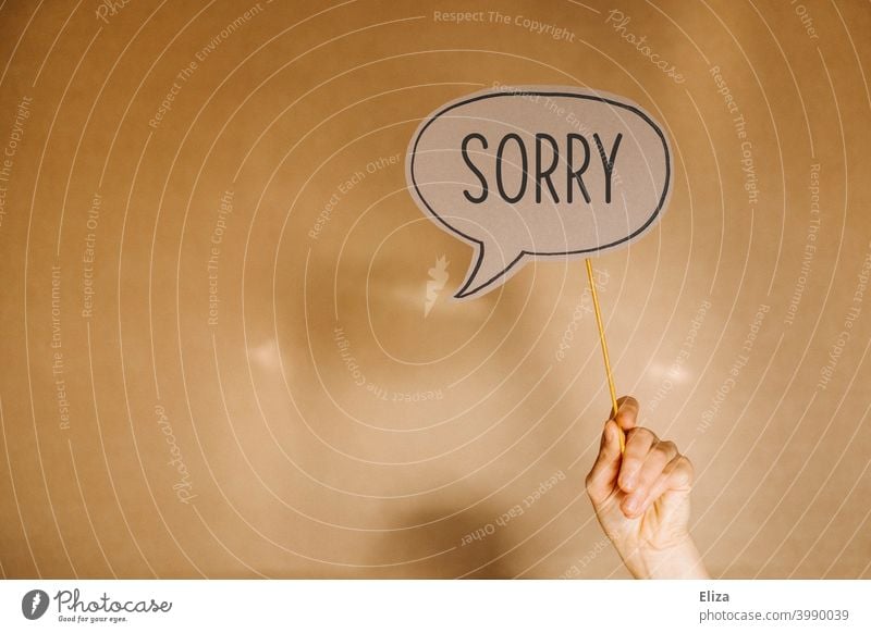 Eine Hand hält eine Sprechblase in der das Wort Sorry geschrieben steht. Entschuldigung. um Entschuldigung bitten Schriftzeichen Reue bereuen Kommunizieren