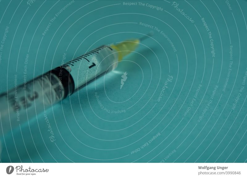 Eine Spritze mit Flüssigkeitstropfen auf türkisem Hintergrund vereinzelt Korona Nahaufnahme Stoß Impfung kalt Grippe Gesundheit Pflege Medikament Medizin Jena