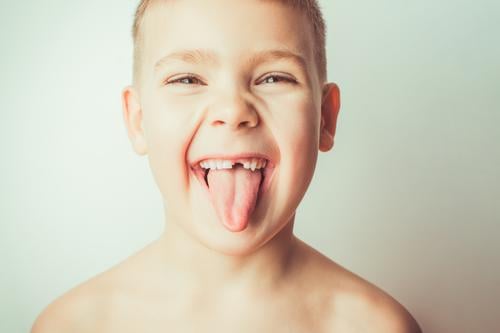 Lustiger Junge ohne Zahn zeigt Zunge wenig Kind Pflege männlich Person Hintergrund Mund Gesicht Porträt Kindheit lustig Zähne Fröhlichkeit weiß schön Lächeln