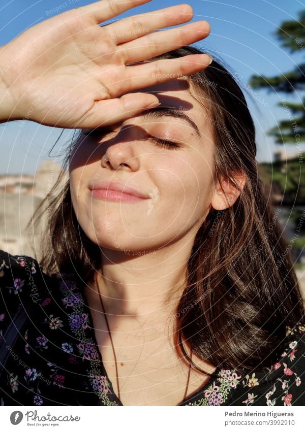 Mädchen mit geschlossenen Augen, das mit der Hand die Sonne abdeckt. Gesundheit Dermatologie Frau Behandlung beunruhigt Sonnenschein heiß Gesichtsbehandlung
