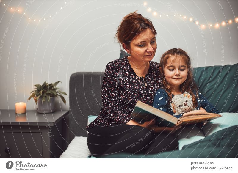 Mutter lesen Buch ihre Tochter im Bett vor dem Schlafengehen. Gutenachtgeschichten für Kind Nacht Schlafenszeit Familie heimwärts Literatur Frau Schlafzimmer