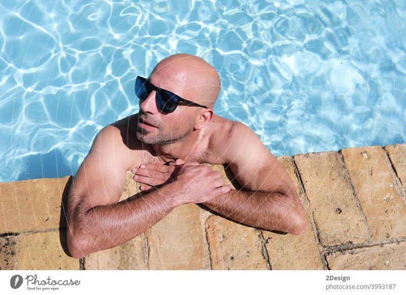 gut aussehend Kerl halb nackt fröhlich Mann lächelnd lachend in blauem Wasser Schwimmbad nass Bräune Schwimmsport Pool kahl Sonnenbrille Sommer jung Glück