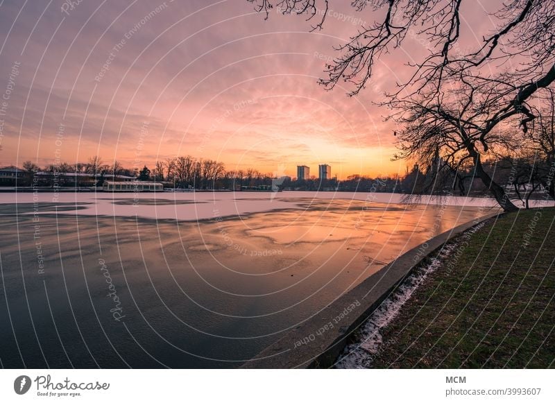 Dramatischer Sonnenuntergang über dem zugefrorenen See im Herastrau Park in Bukarest, Rumänien Sonnenuntergangshimmel Sonnenuntergangsstimmung abendrot