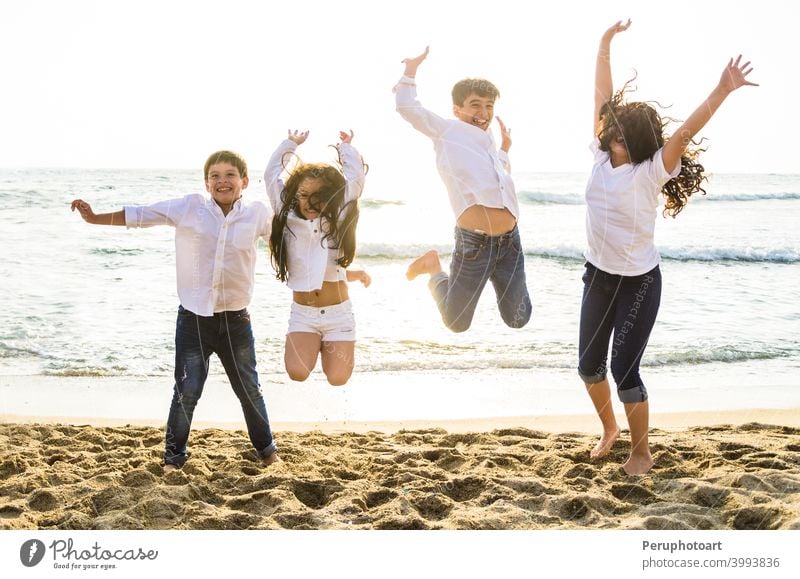 Glückliche Kinder springen zusammen am Strand springend MEER Menschen Familie Wasser Sommer Himmel Sonnenlicht Menschengruppe Sonnenuntergang Urlaub reisen