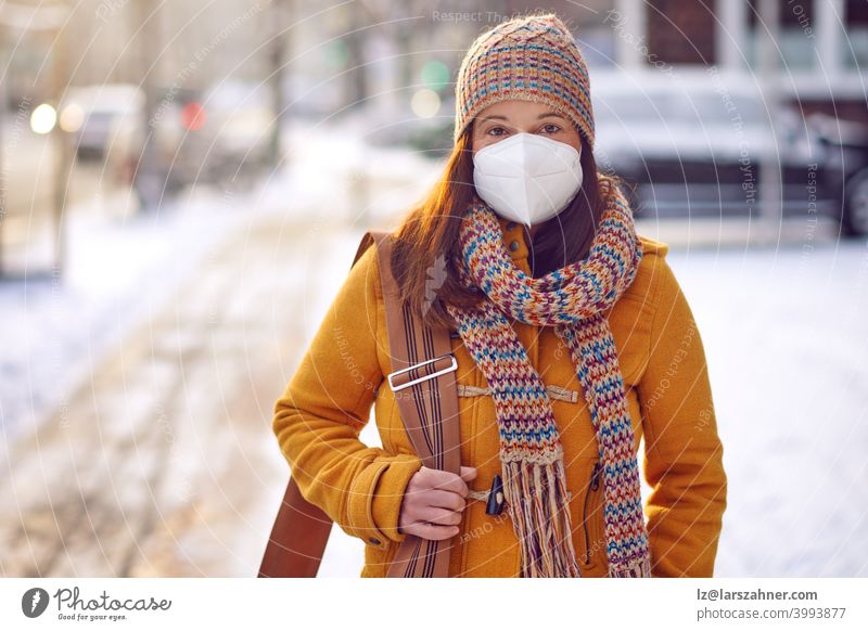Brünette Frau mittleren Alters in Winterkleidung mit Gesichtsmaske im Freien aufgrund des Corona-Virus auf dem Weg zur Arbeit brünett Mundschutz ffp2 Schutz