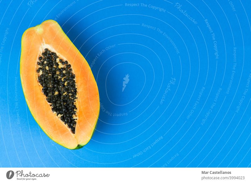 Halbierte Papaya auf blauem Hintergrund. Platz zum Kopieren. Frucht carica Papaya carica tropisch Saatgut reif süß Lebensmittel Blauer Hintergrund Dessert
