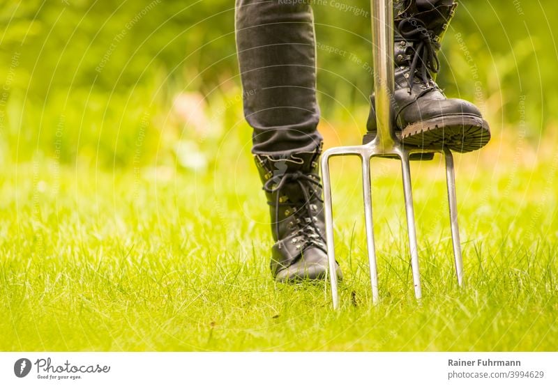 Nahaufnahme von einem Gärtner, der mit seinem Werkzeug in einem Garten steht Grabegabel umgraben kultivieren Hobby Freizeit Arbeitsschuhe Schuhe Gartenarbeit