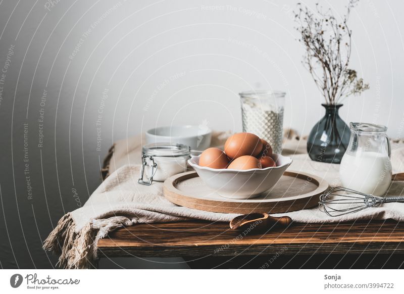 Eier in einer Schüssel und Backzutaten auf einem Leinentischtuch Schalen & Schüsseln Leinentuch Zutaten backen Stillleben Frühstück Tisch Holz rustikal Wand