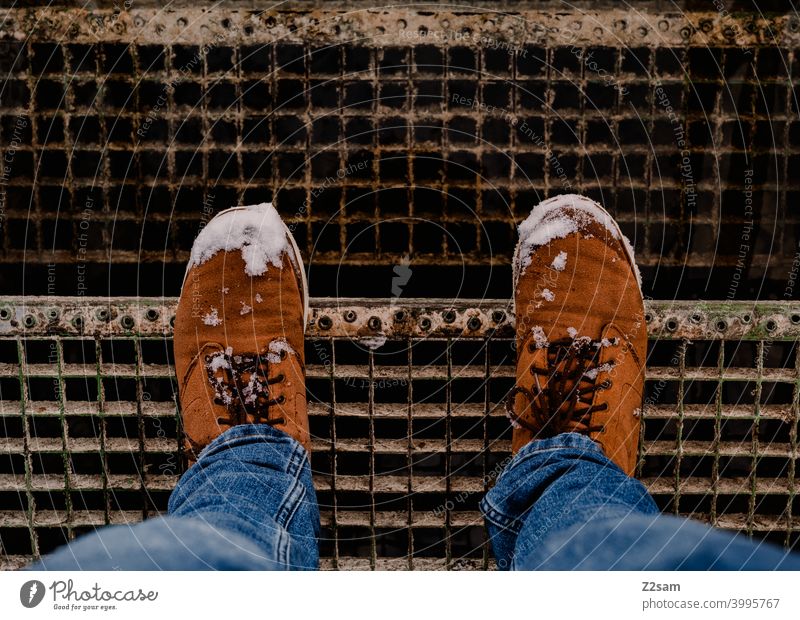 Winterstiefel mit Schnee auf einer Treppe winterspaziergang schnee beine füße winterschuhe wildleder braun jeans blau treppe männerschuhe mann vogelperspektive